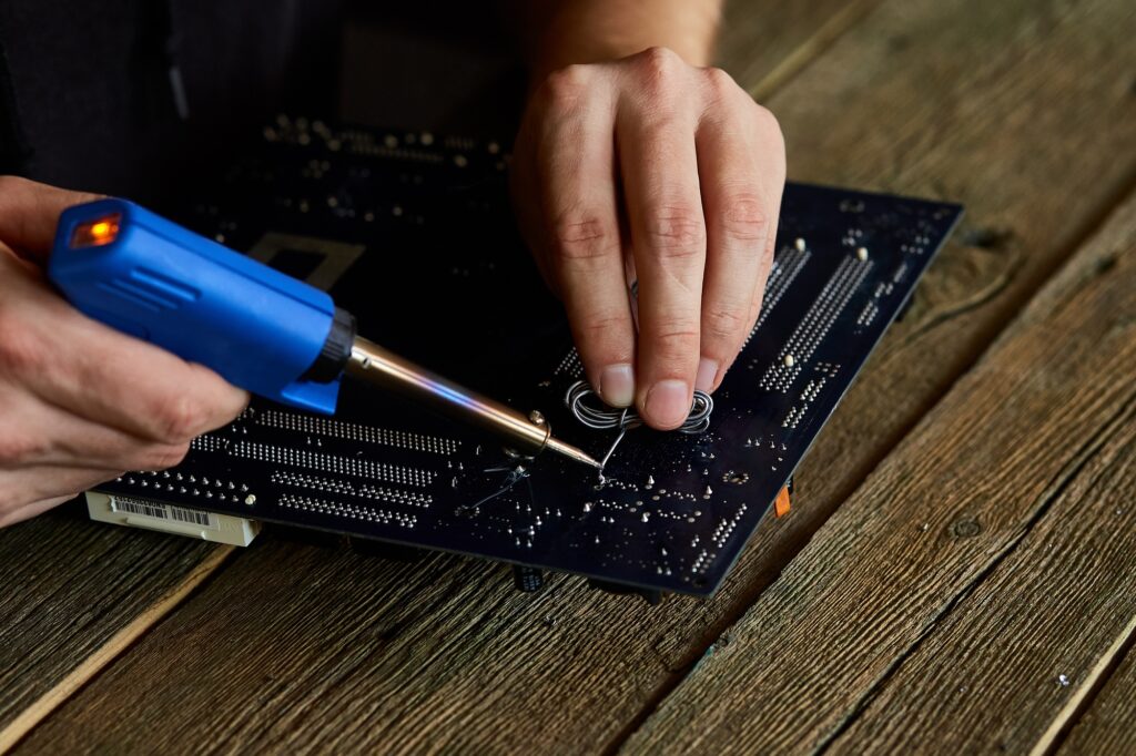 Engineer or technician repair electronic circuit board with soldering iron.